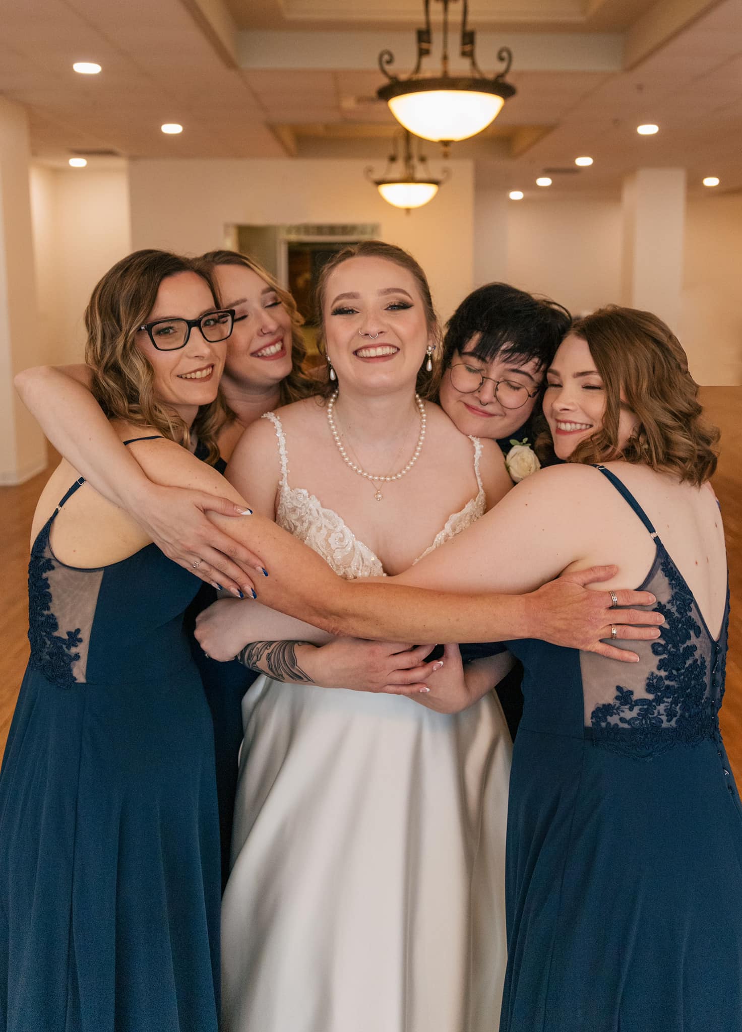 Bride and bridesmaids hugging at queer wedding at Gillioz Theatre