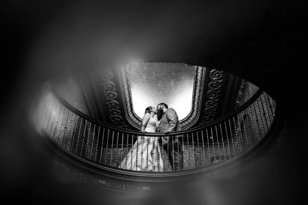 Alternative queer midwest couple kissing in the balcony at their Lord of the Rings-inspired wedding at the Gillioz Theater in Springfield, Missouri