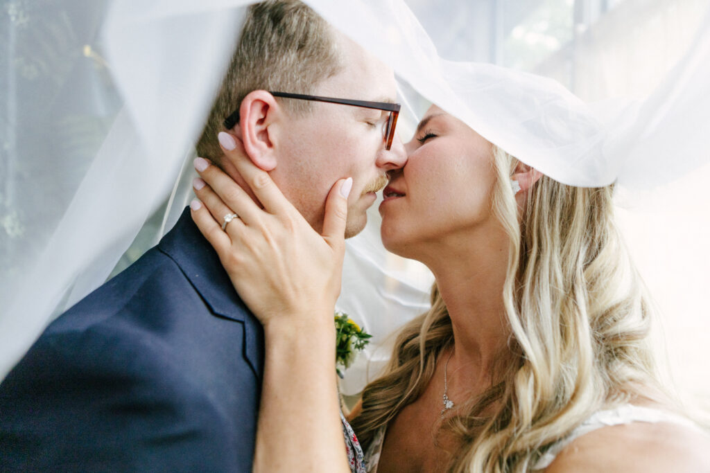 Chelsea Stanford Photographer Springfield MO A weird couple kissing under veil at a Juniper Garden wedding in Fair Grove, MO